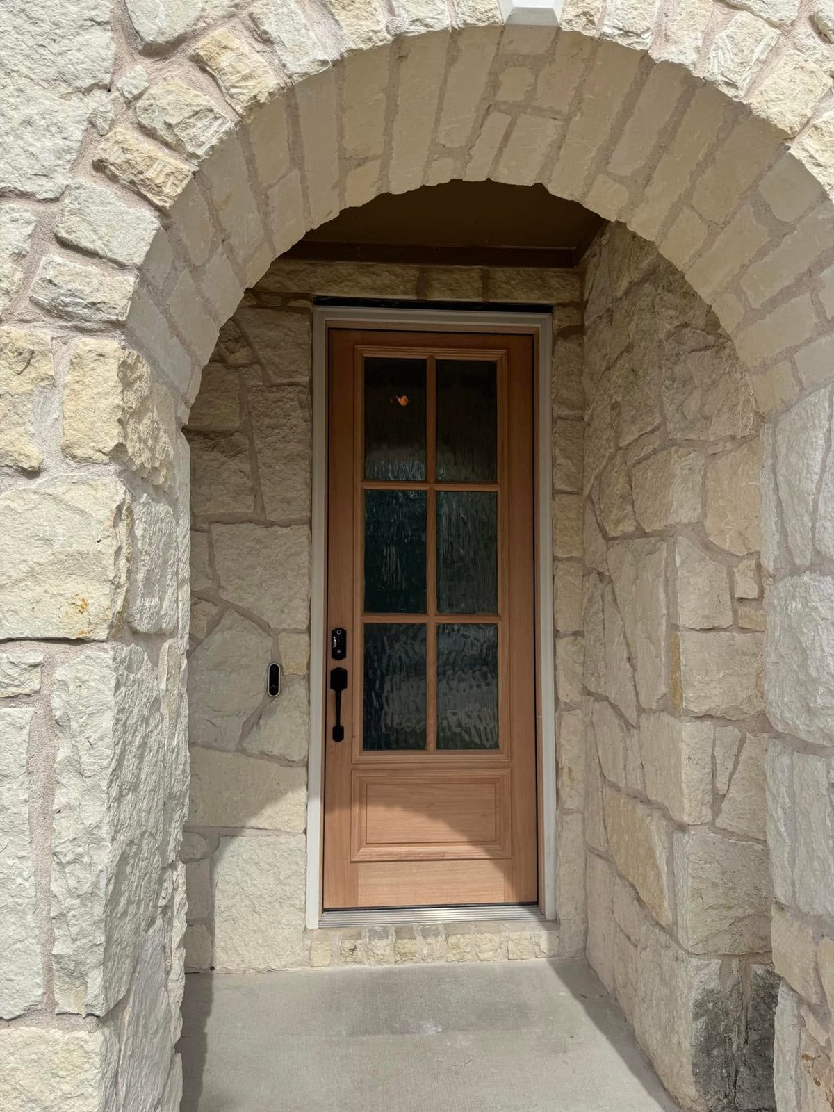 Finished front entry with a stone archway and a new wood front door