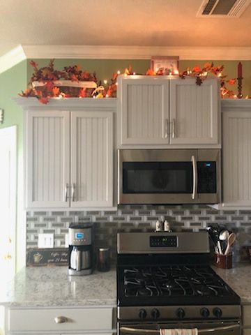 Remodeled kitchen with refinished white cabinets and tile backsplash
